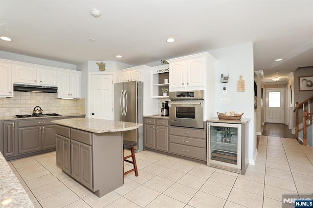 kitchen with appliances with stainless steel finishes, wine cooler, gray cabinetry, light tile patterned floors, and recessed lighting