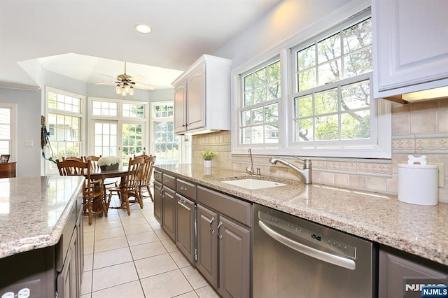 kitchen with stainless steel dishwasher, a sink, light tile patterned flooring, a ceiling fan, and tasteful backsplash