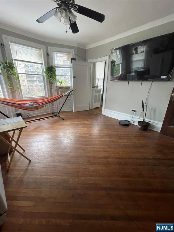 unfurnished dining area featuring baseboards, a ceiling fan, and wood finished floors