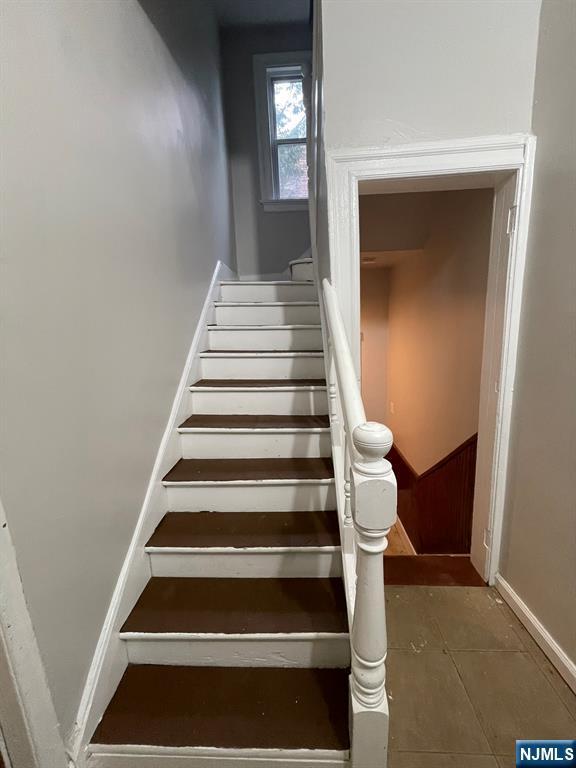 staircase with tile patterned floors and baseboards