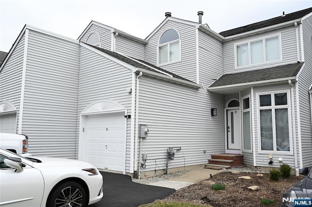 view of side of home with a shingled roof and driveway