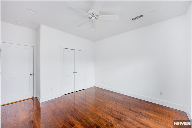 unfurnished bedroom featuring baseboards, visible vents, a closet, and wood finished floors