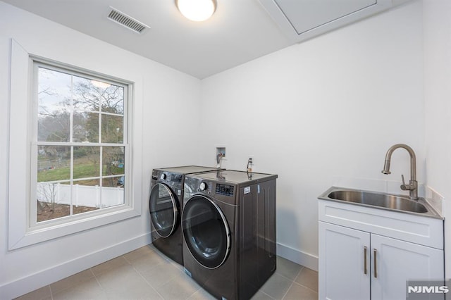 clothes washing area featuring washer and clothes dryer, a sink, baseboards, visible vents, and cabinet space
