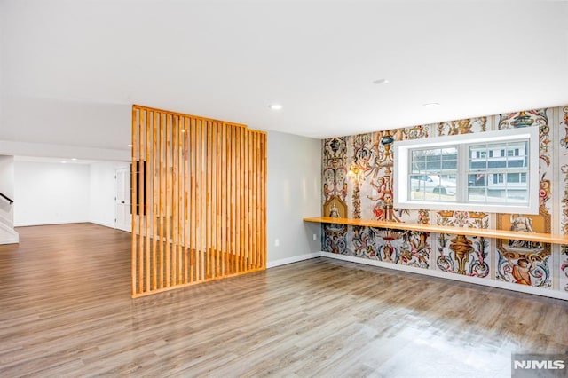 unfurnished room featuring stairs, recessed lighting, baseboards, wallpapered walls, and wood finished floors