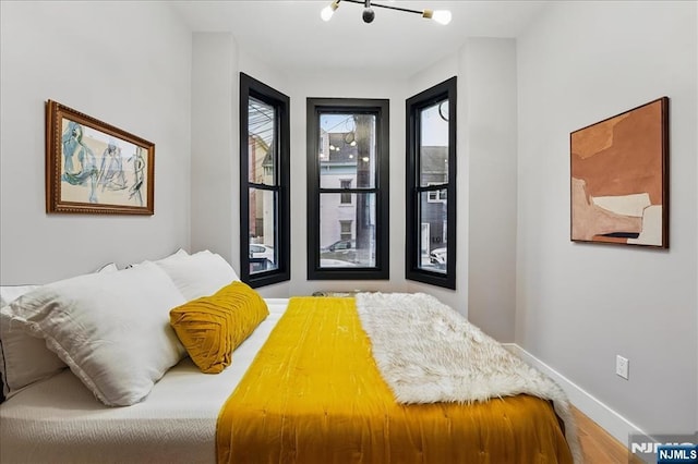 bedroom with baseboards, a chandelier, and wood finished floors