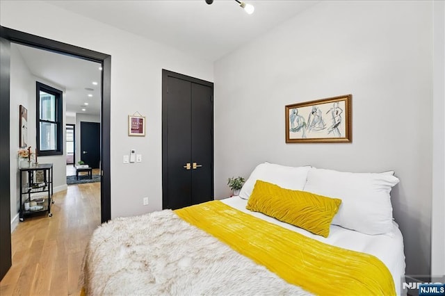 bedroom with a closet, light wood finished floors, baseboards, and recessed lighting