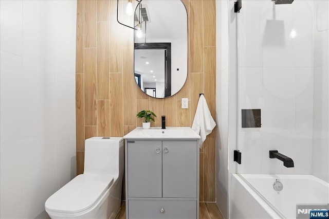 bathroom with vanity, tile walls, shower / bathing tub combination, and toilet