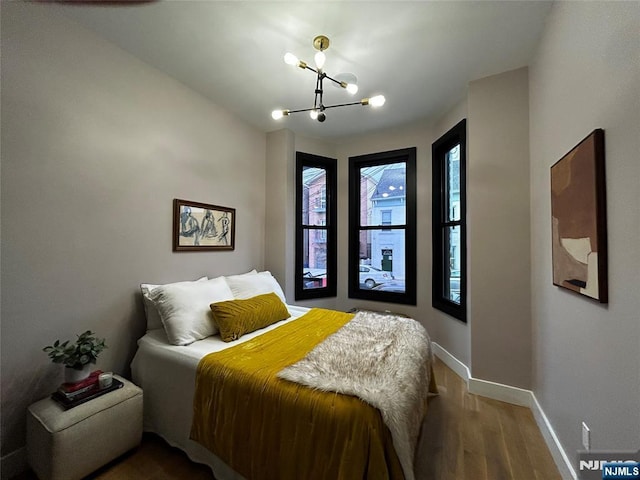 bedroom with baseboards, a chandelier, and wood finished floors