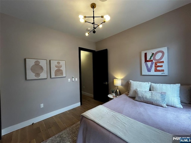 bedroom featuring a notable chandelier, baseboards, and wood finished floors