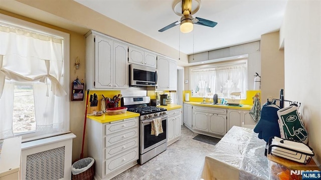 kitchen featuring light countertops, a sink, stainless steel appliances, white cabinets, and ceiling fan