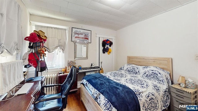 bedroom with dark wood-type flooring and radiator heating unit