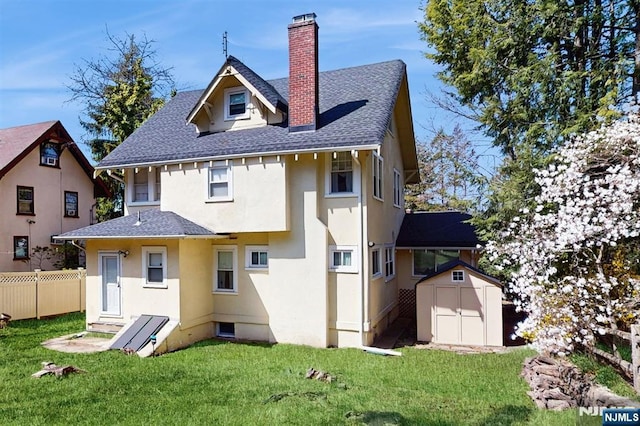 rear view of property with a shed, stucco siding, an outbuilding, fence, and a chimney