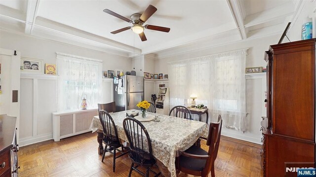 dining space featuring coffered ceiling, beam ceiling, a ceiling fan, radiator, and a decorative wall