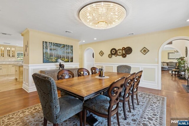 dining room with visible vents, arched walkways, and a wainscoted wall