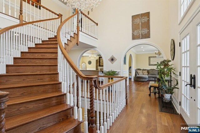 stairway with a healthy amount of sunlight, arched walkways, a high ceiling, and a notable chandelier