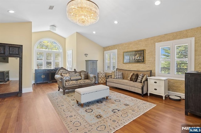 living room with baseboards, a notable chandelier, vaulted ceiling, and a wealth of natural light
