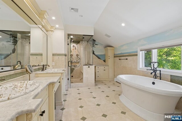 full bath with visible vents, tile walls, wainscoting, a shower stall, and vanity