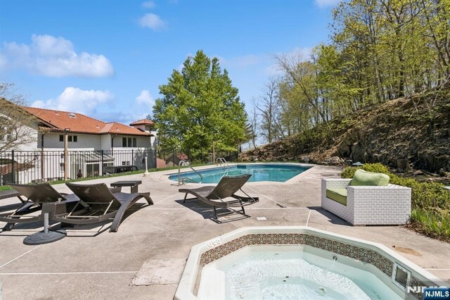 view of swimming pool with a patio, an in ground hot tub, fence, and a fenced in pool