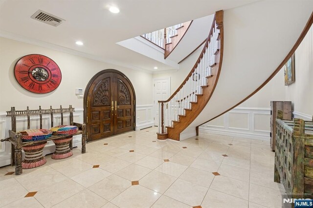 tiled entrance foyer with visible vents, a decorative wall, stairway, recessed lighting, and a skylight
