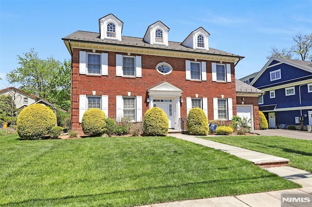 321 Rutland Ave, Teaneck, NJ 07666 - colonial-style house featuring brick siding, an attached garage, driveway, and a front lawn