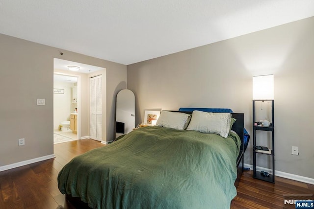 bedroom with baseboards, ensuite bathroom, wood finished floors, and a closet