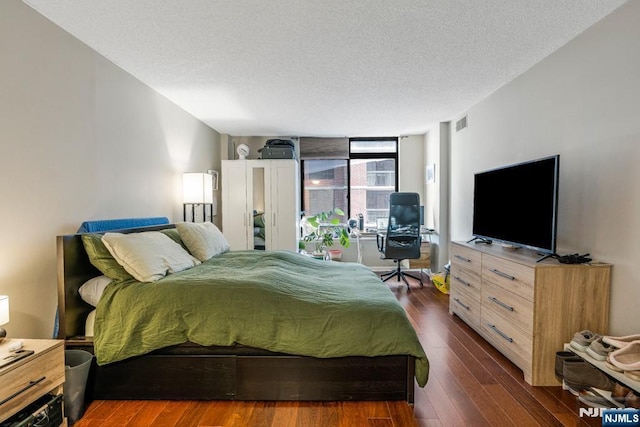 bedroom with visible vents, a textured ceiling, and dark wood finished floors