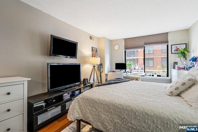 bedroom featuring visible vents, a textured ceiling, and wood finished floors