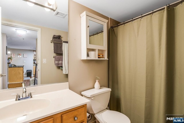 full bathroom with visible vents, toilet, and vanity