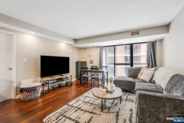 living area with wood finished floors, a textured ceiling, baseboards, and visible vents