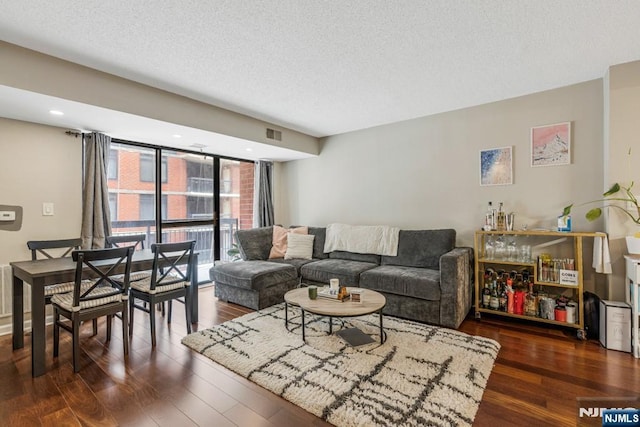 living room featuring visible vents, a textured ceiling, and wood finished floors