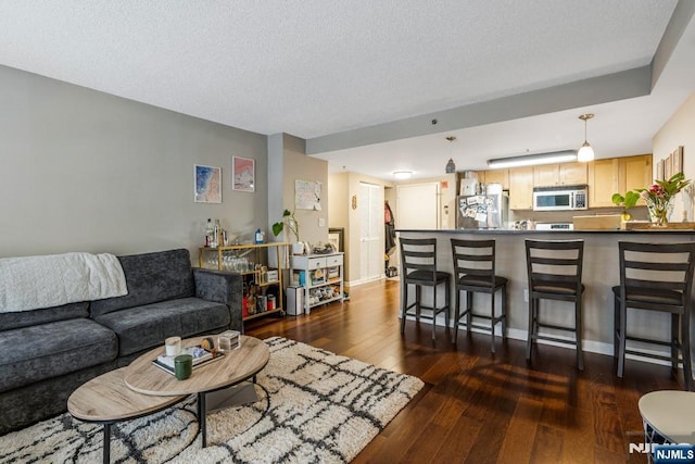 living area featuring dark wood finished floors, baseboards, and a textured ceiling