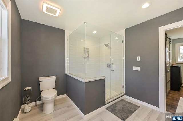 bathroom featuring a shower stall, wood finished floors, baseboards, toilet, and recessed lighting