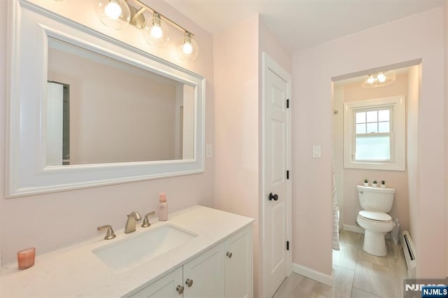 bathroom featuring baseboards, vanity, a baseboard radiator, and toilet