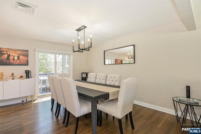 dining area featuring dark wood-type flooring, visible vents, baseboards, and a notable chandelier