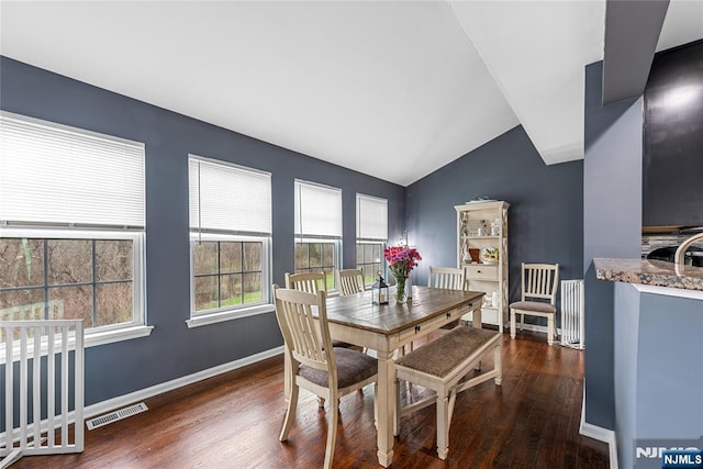 dining area with wood finished floors, baseboards, lofted ceiling, and visible vents