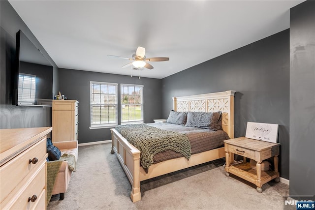 bedroom featuring light colored carpet, baseboards, and a ceiling fan