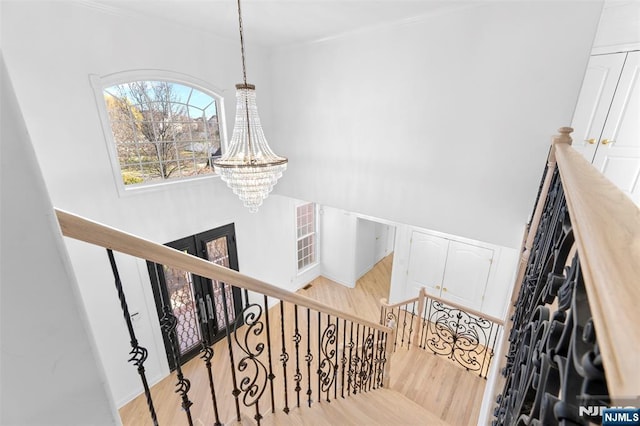 stairs with wood finished floors and an inviting chandelier