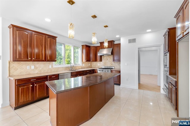 kitchen featuring a sink, backsplash, appliances with stainless steel finishes, under cabinet range hood, and visible vents