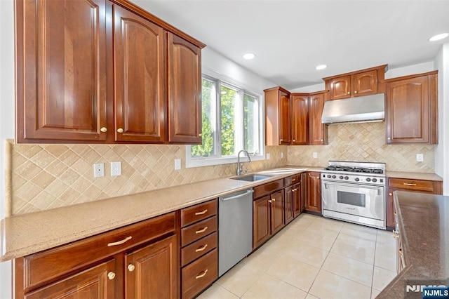 kitchen featuring stainless steel appliances, under cabinet range hood, a sink, light stone counters, and light tile patterned floors