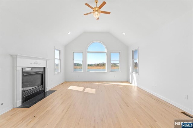 unfurnished living room with a ceiling fan, a fireplace with flush hearth, lofted ceiling, and light wood-type flooring