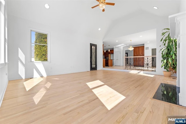 unfurnished living room with high vaulted ceiling, a ceiling fan, light wood-style flooring, baseboards, and recessed lighting