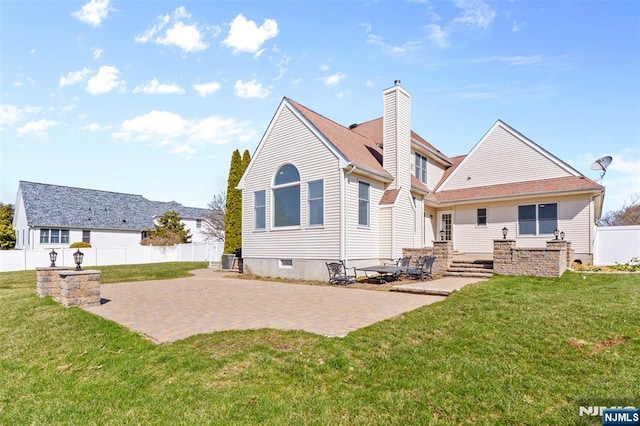 rear view of house featuring a patio, a chimney, fence, and a yard
