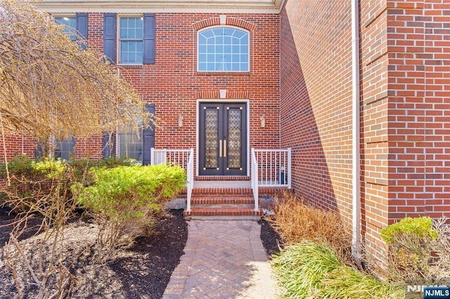 view of exterior entry featuring french doors and brick siding