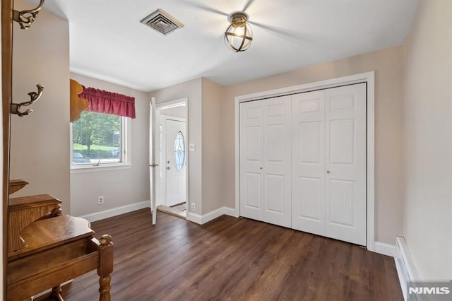 foyer entrance featuring baseboards, visible vents, and dark wood finished floors