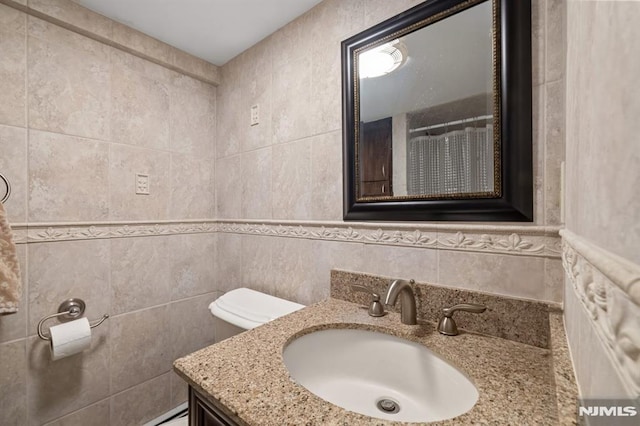 full bathroom featuring tile walls, vanity, and toilet