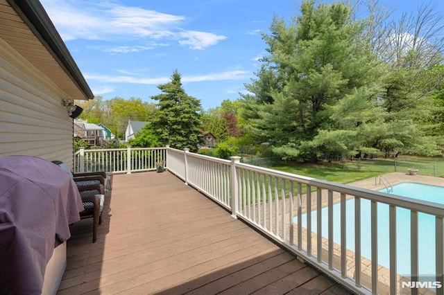 deck with a lawn, a fenced backyard, and an outdoor pool