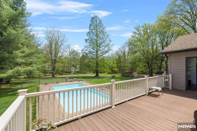 wooden deck featuring a lawn and a fenced in pool