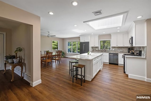 kitchen with backsplash, a kitchen island, visible vents, white cabinets, and stainless steel appliances