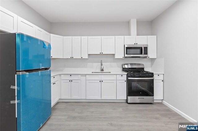 1457 67th St, North Bergen, NJ 07047 - kitchen with light wood-style flooring, light countertops, a sink, and appliances with stainless steel finishes