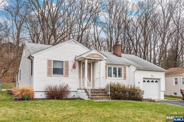 view of front of home with a chimney, a garage, a front yard, and driveway